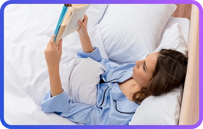 Kobieta w niebieskiej koszuli nocnej czyta książkę, leżąc w łóżku i relaksując się przed snem w wygodnej domowej sypialni.